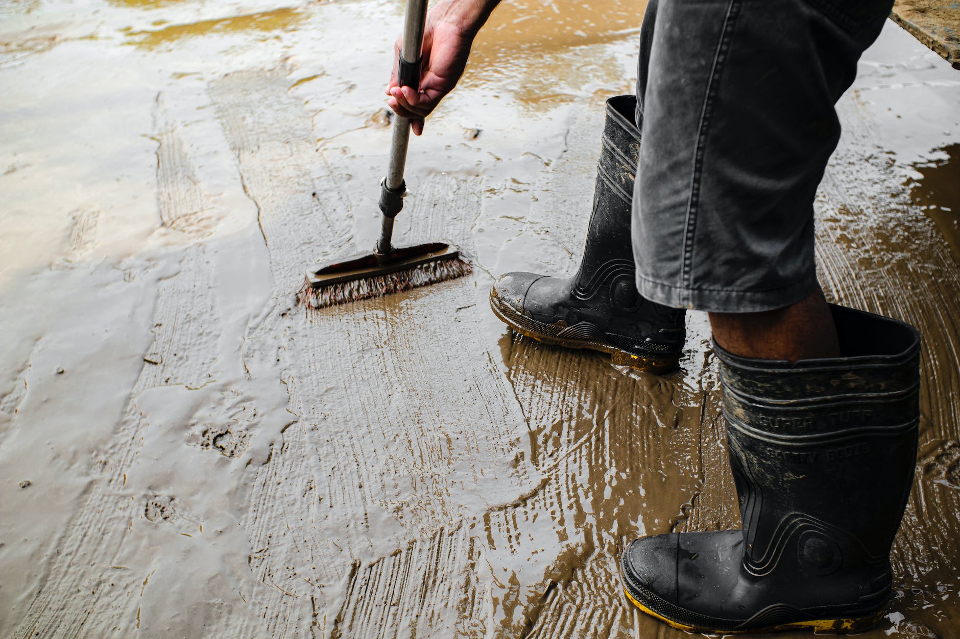 crop workman in rubber boots priming concrete floor