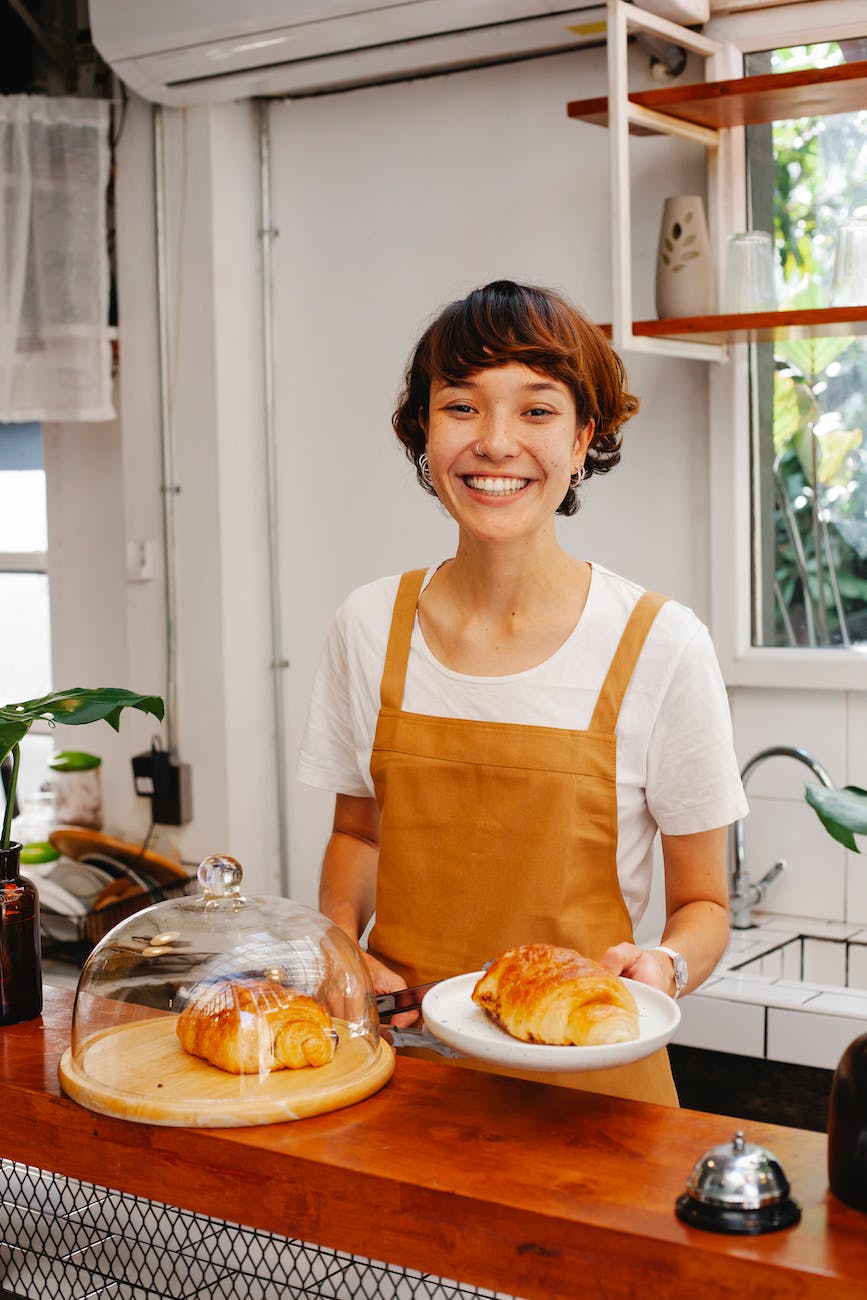 cheerful woman serving croissants in cafe